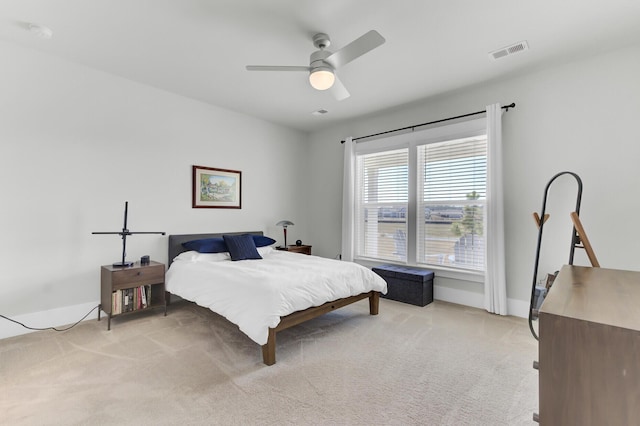 bedroom with visible vents, light colored carpet, and a ceiling fan