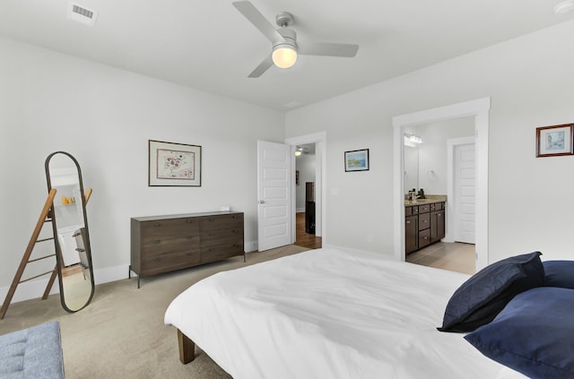 bedroom featuring visible vents, light carpet, ensuite bathroom, baseboards, and ceiling fan