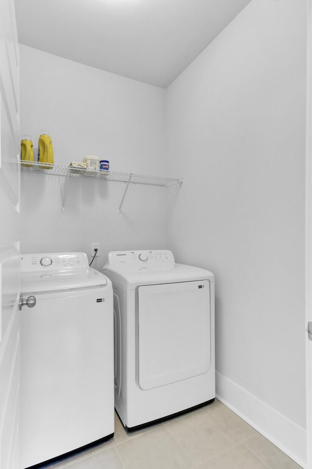 laundry room with washer and dryer, laundry area, light tile patterned floors, and baseboards