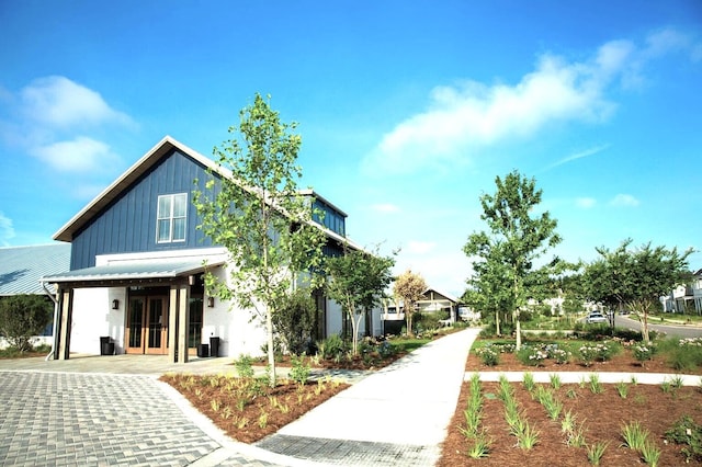 exterior space featuring board and batten siding, metal roof, french doors, and a standing seam roof