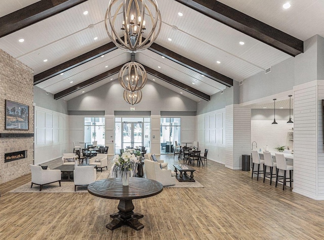 interior space featuring beamed ceiling, a fireplace, wood finished floors, a notable chandelier, and high vaulted ceiling