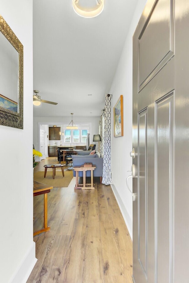 hall featuring light wood finished floors and baseboards