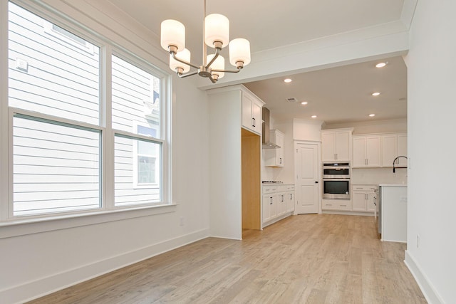 kitchen featuring light wood-style flooring, plenty of natural light, white cabinetry, stainless steel double oven, and a chandelier