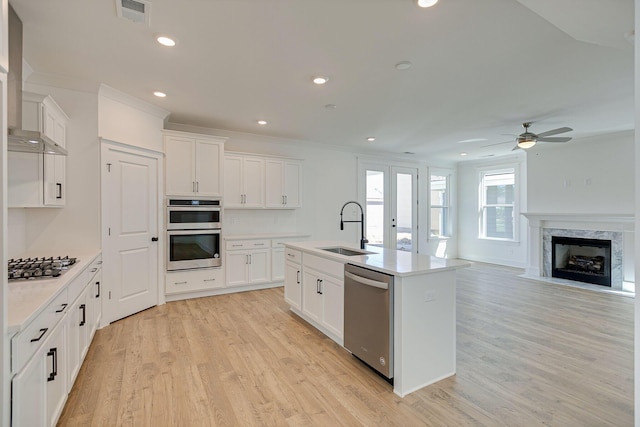 kitchen featuring visible vents, a sink, stainless steel appliances, light wood-style floors, and ceiling fan