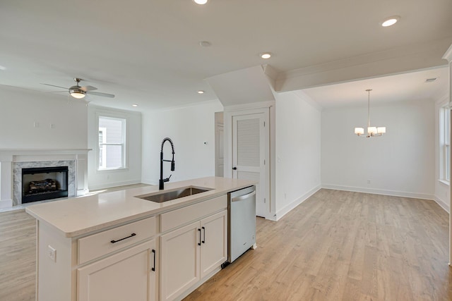 kitchen with a high end fireplace, light wood finished floors, dishwasher, ceiling fan with notable chandelier, and a sink