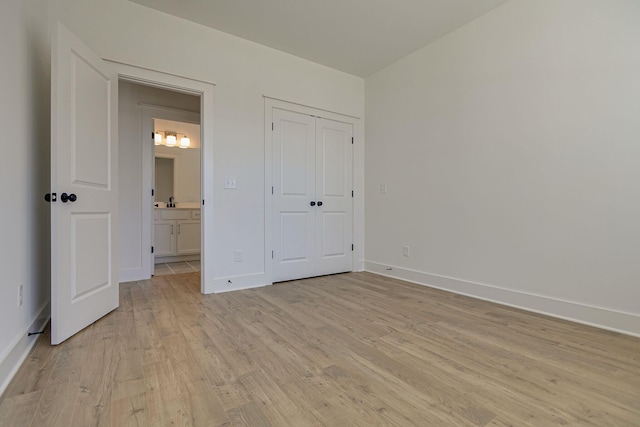 unfurnished bedroom with a closet, baseboards, and light wood-style flooring