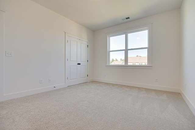 spare room with visible vents, baseboards, and light colored carpet