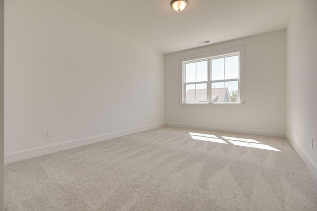 empty room featuring light colored carpet, visible vents, and baseboards