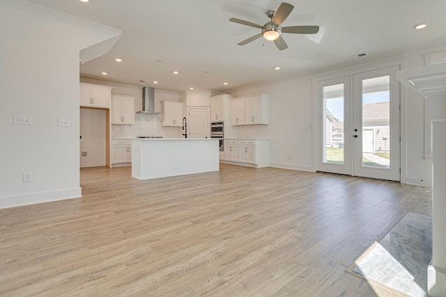 unfurnished living room featuring visible vents, light wood-style flooring, a ceiling fan, ornamental molding, and a sink