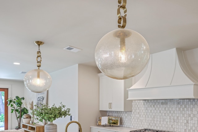 974 Cliffwood Dr, Mount Pleasant, SC 29464 - kitchen view of decorative backsplash, white cabinets, light countertops, pendant lighting, and premium range hood