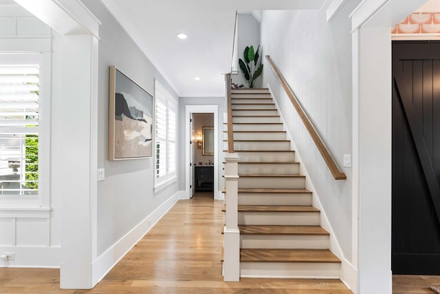 staircase with wood finished floors, baseboards, and recessed lighting