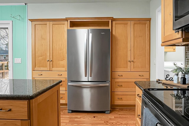 kitchen with stainless steel appliances, light wood-type flooring, and dark stone countertops