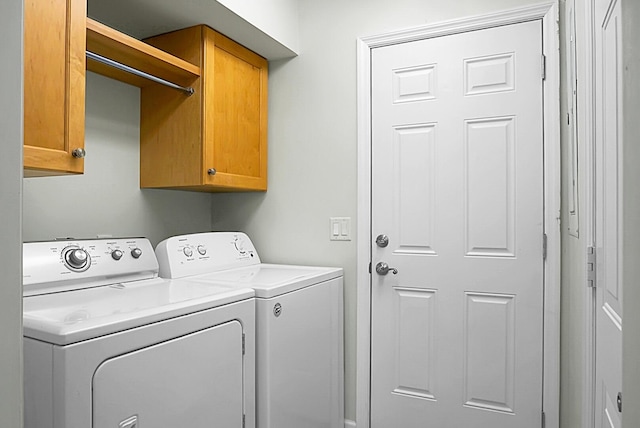 clothes washing area featuring cabinets and washer and dryer