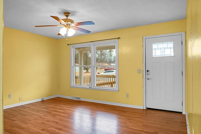 foyer entrance featuring light wood-style floors, baseboards, visible vents, and a wealth of natural light