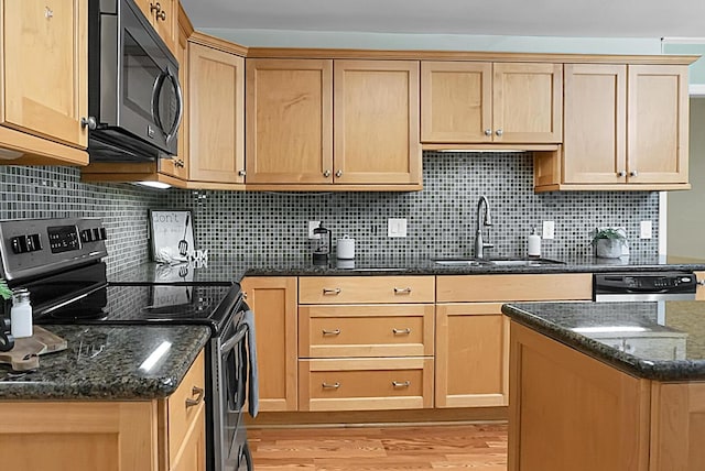 kitchen featuring dishwasher, sink, dark stone countertops, stainless steel range with electric stovetop, and light wood-type flooring