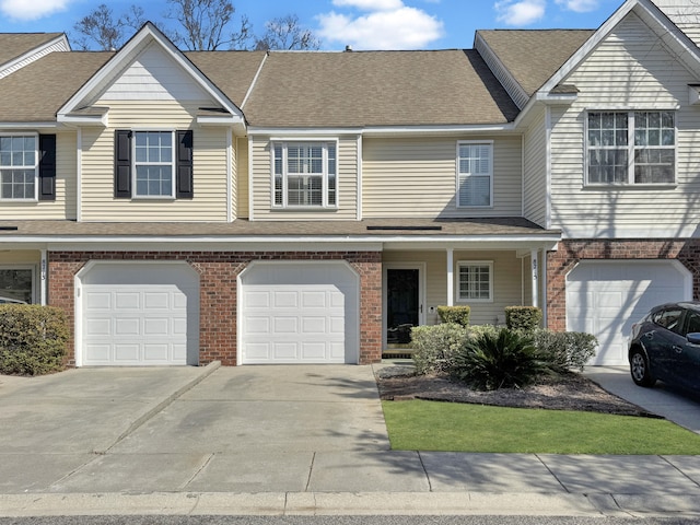 view of property with driveway, a shingled roof, a garage, and brick siding