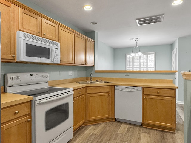 kitchen featuring white appliances, visible vents, light countertops, pendant lighting, and a sink