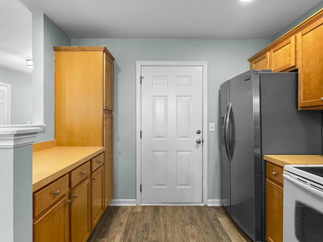 kitchen featuring brown cabinets, dark wood finished floors, white range with electric cooktop, light countertops, and baseboards