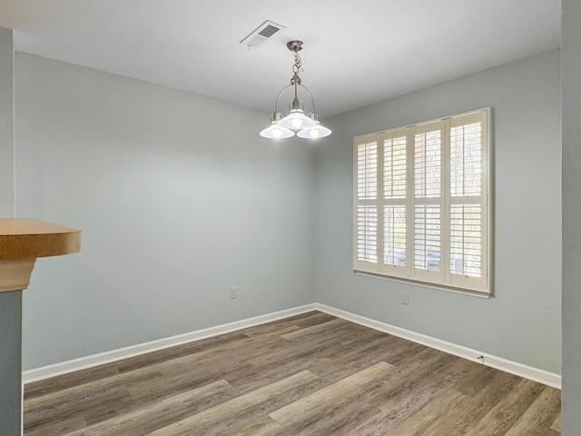 unfurnished dining area with baseboards, visible vents, and wood finished floors