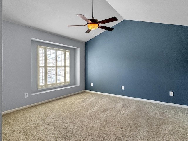 carpeted empty room with vaulted ceiling, a ceiling fan, and baseboards