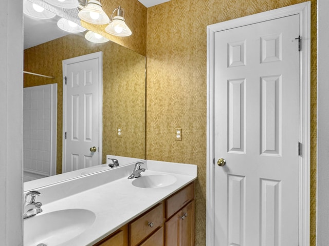 bathroom with double vanity, wallpapered walls, and a sink