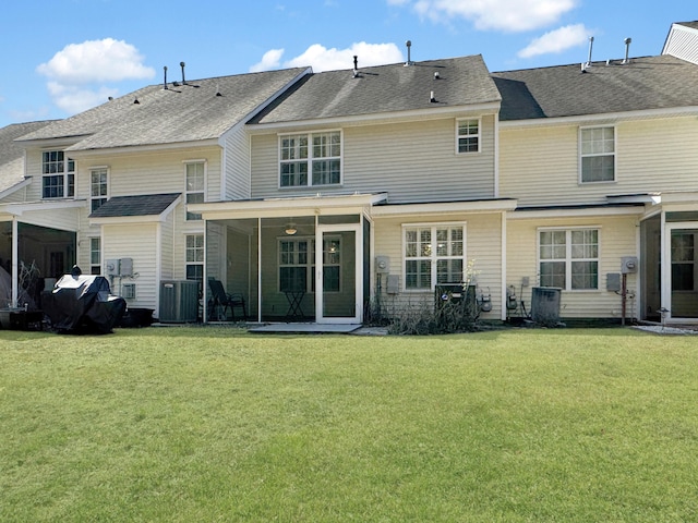 rear view of house featuring roof with shingles, central AC unit, and a yard