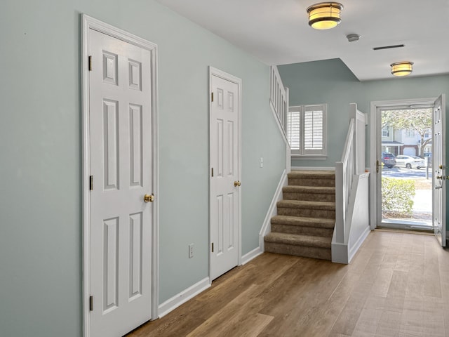 foyer with baseboards, stairway, and light wood-style floors