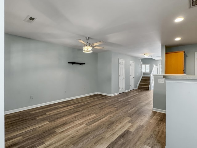 spare room featuring visible vents, stairway, dark wood-type flooring, a ceiling fan, and baseboards