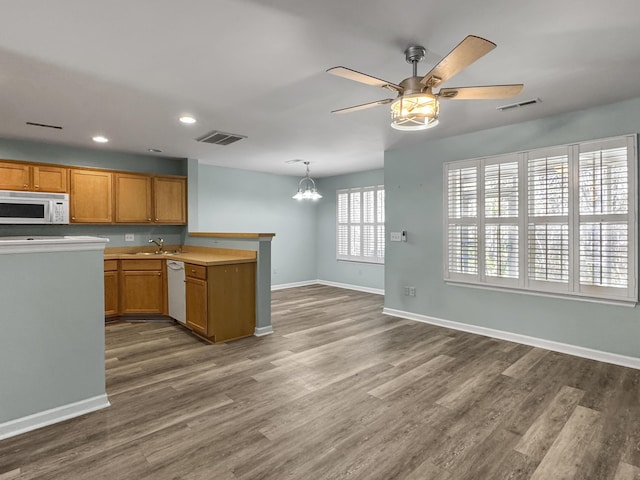 kitchen with decorative light fixtures, brown cabinets, light countertops, visible vents, and white appliances