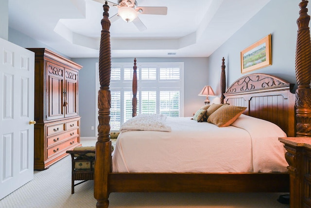 bedroom featuring a tray ceiling, ceiling fan, and light colored carpet