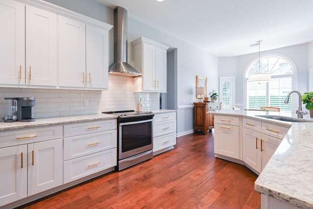 kitchen featuring white cabinetry, stainless steel electric range, decorative light fixtures, sink, and wall chimney range hood