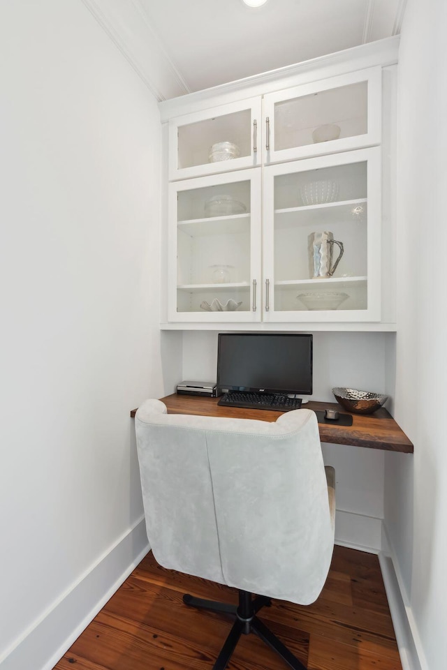 office area featuring baseboards, wood finished floors, and built in study area