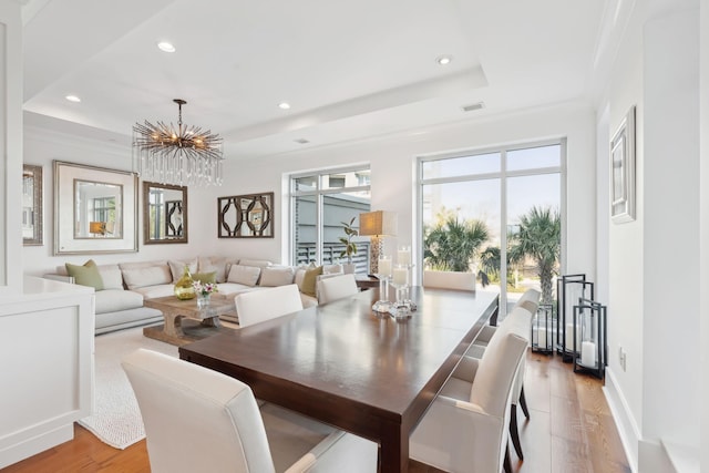 dining space featuring light wood-style floors, visible vents, a raised ceiling, and recessed lighting