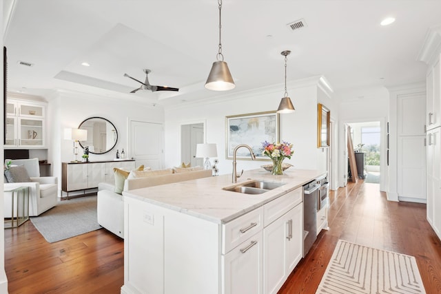 kitchen featuring open floor plan, visible vents, a sink, and an island with sink