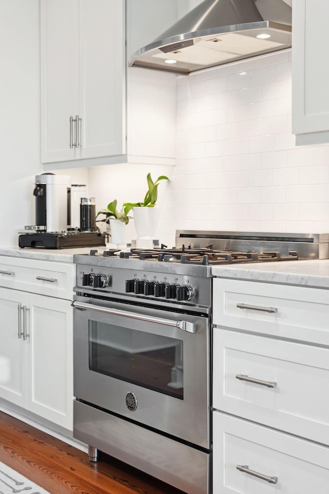 kitchen with tasteful backsplash, light countertops, high end stainless steel range oven, and exhaust hood