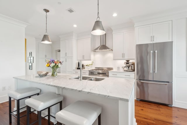 kitchen with wall chimney range hood, dark wood-style floors, visible vents, and high end appliances