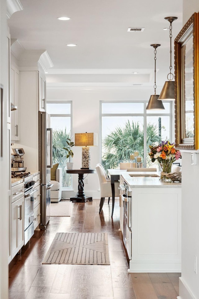 kitchen featuring visible vents, appliances with stainless steel finishes, white cabinets, and pendant lighting