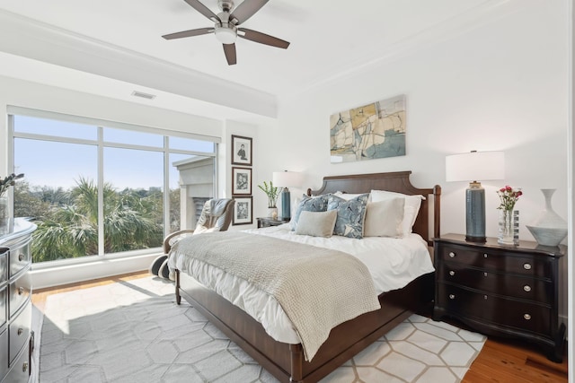 bedroom featuring ceiling fan, ornamental molding, light wood-type flooring, and visible vents