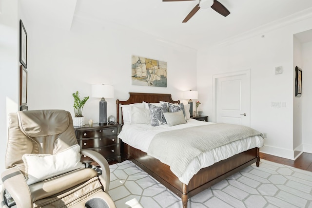 bedroom featuring a ceiling fan, baseboards, wood finished floors, and ornamental molding