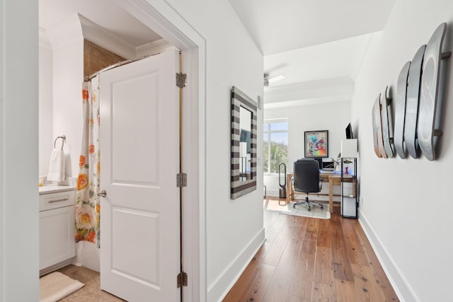 hall with baseboards, light wood-style floors, and crown molding