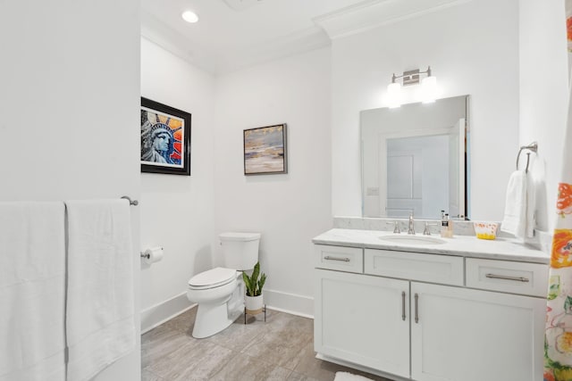 bathroom with crown molding, vanity, toilet, and baseboards