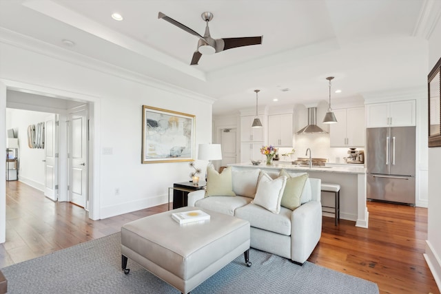 living room featuring baseboards, a ceiling fan, wood finished floors, a tray ceiling, and recessed lighting