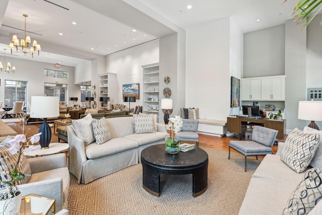 living room featuring an inviting chandelier, light wood-style flooring, a high ceiling, and recessed lighting