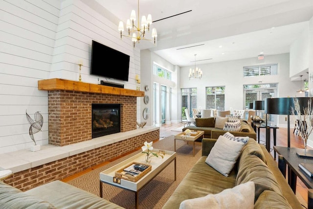 living room with baseboards, a high ceiling, a brick fireplace, and an inviting chandelier