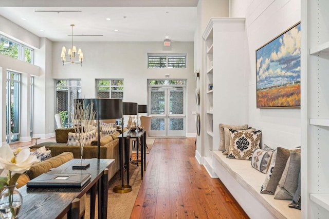 interior space featuring a chandelier, wood-type flooring, a towering ceiling, and baseboards