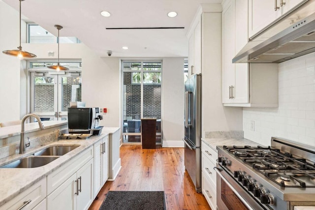 kitchen featuring stainless steel appliances, a sink, white cabinetry, and under cabinet range hood