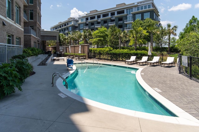 community pool featuring fence and a patio