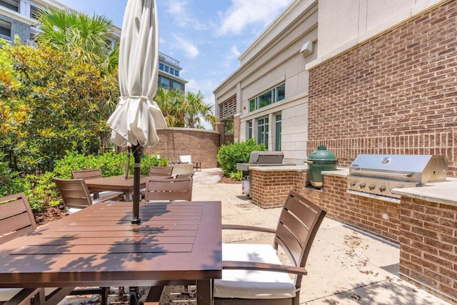 view of patio featuring outdoor dining space, fence, grilling area, and an outdoor kitchen