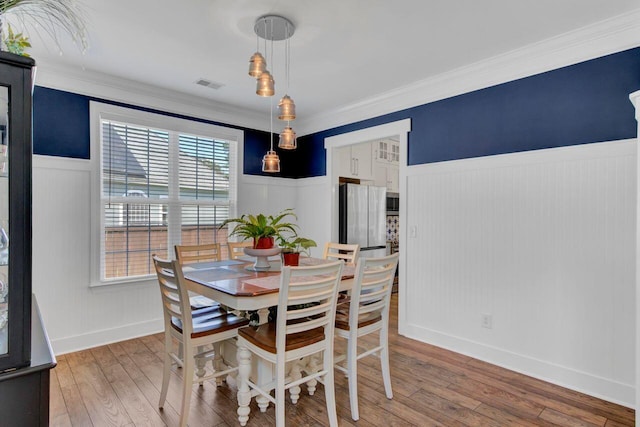 dining space featuring hardwood / wood-style flooring and crown molding