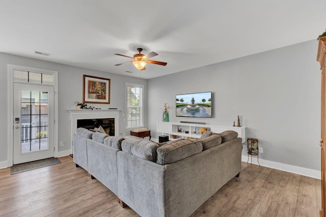 living room with a wealth of natural light, ceiling fan, and light hardwood / wood-style floors